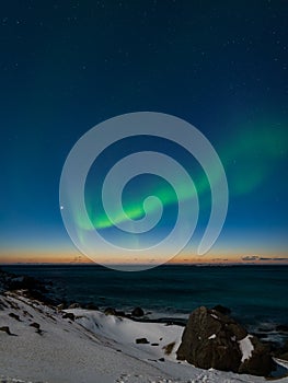 Spectacular dancing green strong northern lights over the famous round boulder beach near Uttakleiv on the Lofoten islands in