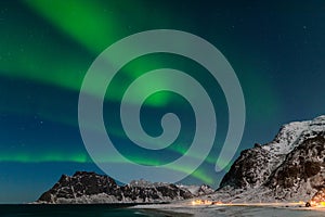 Spectacular dancing green strong northern lights over the famous round boulder beach near Uttakleiv on the Lofoten islands in