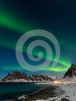 Spectacular dancing green strong northern lights over the famous round boulder beach near Uttakleiv on the Lofoten islands in