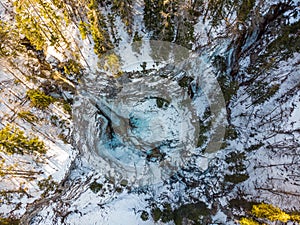 Spectacular drop down view of waterfall falling over rocky forest ledge.