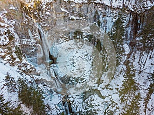 Spectacular drop down view of waterfall falling over rocky forest ledge.