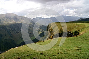 Spectacular green mountain landscape on sunny day with mountain peaks covered by clouds and green sunny hills