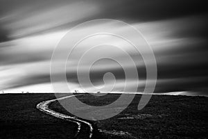 Spectacular long exposure view of clouds above a path on a hill