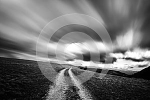 Spectacular long exposure view of clouds above a path on a hill