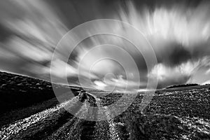 Spectacular long exposure view of clouds above a path on a hill