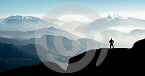 Spectacular mountain ranges silhouettes. Man reaching summit enjoying freedom.
