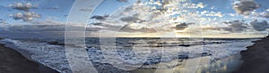 Spectacular  panoramic sunset on the Roman coast in Ostia Lido with waves breaking on the shore and  blue and golden sky spreads a