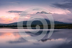 Spectacular reflection of the mountains on a lake with mist under the midnight sun, fairy tale atmosphere in the Vesteralen