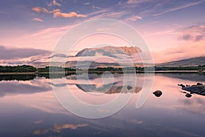 Spectacular reflection of the mountains on a lake with mist under the midnight sun, fairy tale atmosphere in the Vesteralen