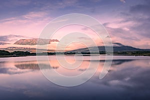 Spectacular reflection of the mountains on a lake with mist under the midnight sun, fairy tale atmosphere in the Vesteralen