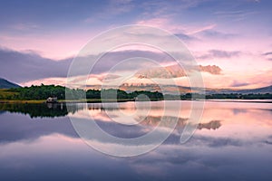 Spectacular reflection of the mountains on a lake with mist under the midnight sun, fairy tale atmosphere in the Vesteralen