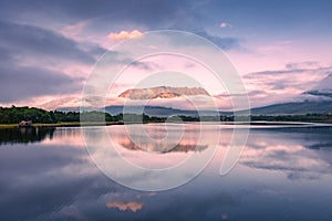 Spectacular reflection of the mountains on a lake with mist under the midnight sun, fairy tale atmosphere in the Vesteralen