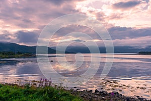 Spectacular reflection of the mountains on a lake with mist under the midnight sun, fairy tale atmosphere in the Vesteralen