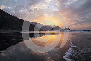 Spectacular twilight reflecting in the calm waves washing the wild Benijo beach or Playa de Benijo, Tenerife, Canary Islands