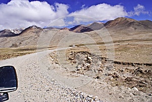 Spectacular View of the gigantic mountain range Kanchenjunga and the rugged barren road leading to Gurudongmar Lake