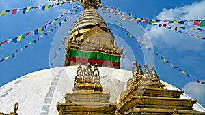 Spectacular view of the golden stupa of the Boudhanath Buddhist temple in Patan adorned with colored prayer flags and a blue sky