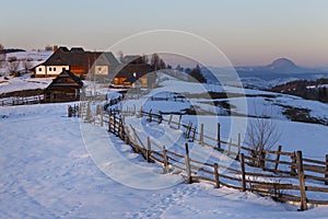 Spectacular winter landscape. Winter sunset, old rural mountain wooden chalets and snowy hills near Brasov, Transylvania