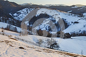 Spectacular winter landscape. Winter sunset, old rural mountain wooden chalets and snowy hills near Brasov, Transylvania