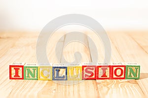 Spectacular wooden cubes with the word INCLUSION on a wooden surface