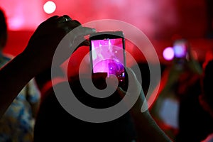 Spectator films a stage performance at a concert.