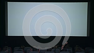 Spectators applaud in anticipation of movie session in front of white screen