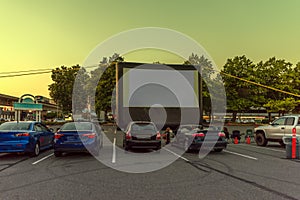 Spectators at a car parking lot with cars, an inflatable screen