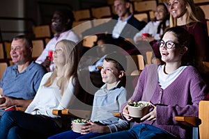 Spectators eating popcorn and watching a movie at cinema