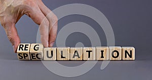 Speculation or regulation symbol. Businessman turns wooden cubes, changes the word speculation to regulation. Beautiful grey