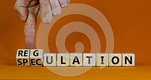 Speculation or regulation symbol. Businessman turns wooden cubes, changes the word speculation to regulation. Beautiful orange