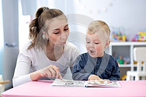 Speech therapist teaching letter pronunciation to kid boy in classroom