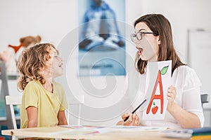 Speech therapist working with a child on a correct pronunciation