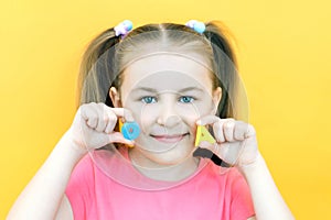 Speech therapy. Toddler girl holding the letter O and A in her hands. Classes with a speech therapist. Girl on isolated yellow