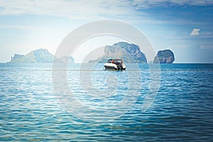 Speed boat floating on the sea with island and blue sky background at Railay Beach.