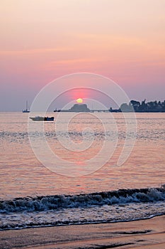 A speed boat sunsetting casting a pink glow over Dona Paula bay, Panjim, Goa