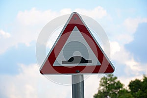 Speed bump sign. Triangle traffic sign warning there is a threshold coming up in the road. Symbol against a blue sky with clouds