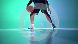 Speed and dynamics. Male basketball player in motion with ball, dribbling on gradient green, cyan background in neon