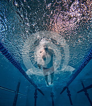 Speed and endurance. Young man, professional swimming athlete in motion, training, swimming in pool