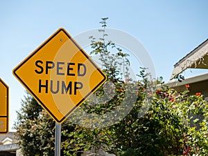 Speed hump yellow street sign in a local neighborhood street