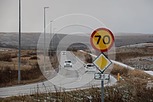 Speed limit road sign with cars moving along the road