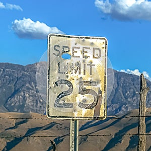 Speed limit sign against fence mountain and sky