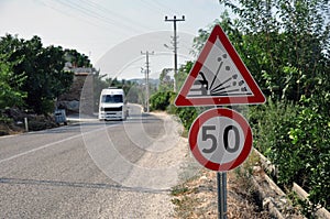 Speed limit sign in countryside on a summer evening. The speed limit is 50 km h on a gravel road.