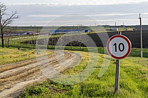 Speed limit sign standing on the side of an unpaved road