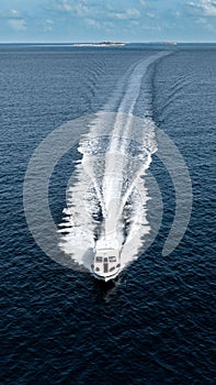 Speedboat cruising across a calm body of water beneath a cloudy sky