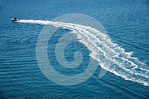 Speedboat runs fast in the open sea and leaves the engine`s wake in the water