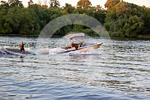 Speedboat towing an athlete on a Board against the background of the forest. Athlete water skiing and having fun.