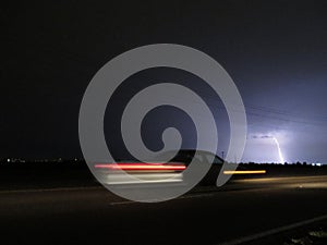 Speeding Car Blurred for Motion on Road with Lightning Strike