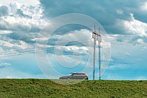 Speeding car on country road with electricity pylon in background