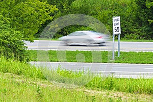 Speeding Car Streaks By Speed Limit Sign