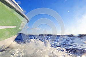 Speeding fishing motor boat with drops of water. Blue ocean sea water wave reflections with fast fishing yacht. Motor boat in the