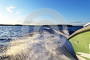 Speeding fishing motor boat with drops of water. Blue ocean sea water wave reflections with fast fishing yacht. Motor boat in the